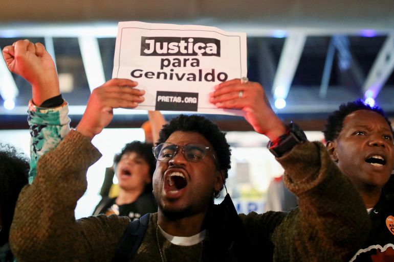 A protester holds up a sign that reads, "Justiça para Genivaldo."