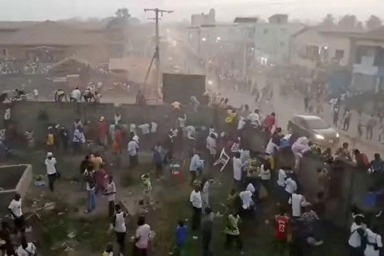 People scramble in Nzerekore, Guinea, where local officials said a deadly crush ensued at a stadium following fan clashes during a soccer match