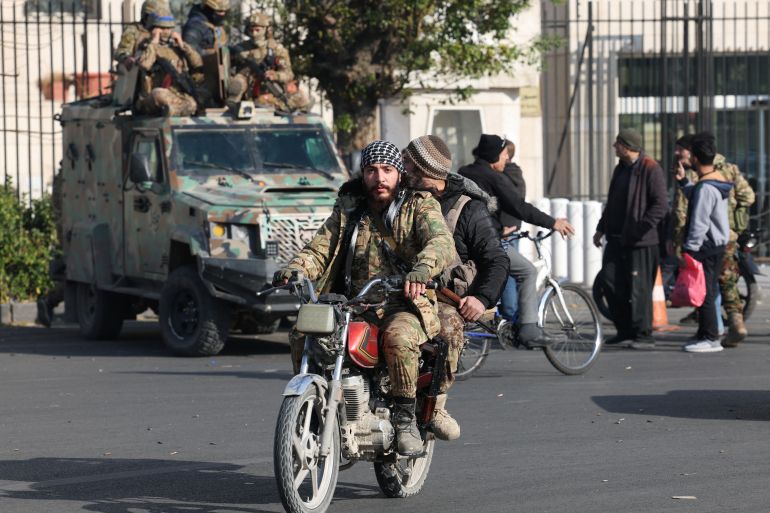 Rebel fighters ride a motorbike, after rebels seized the capital and ousted President Bashar al-Assad