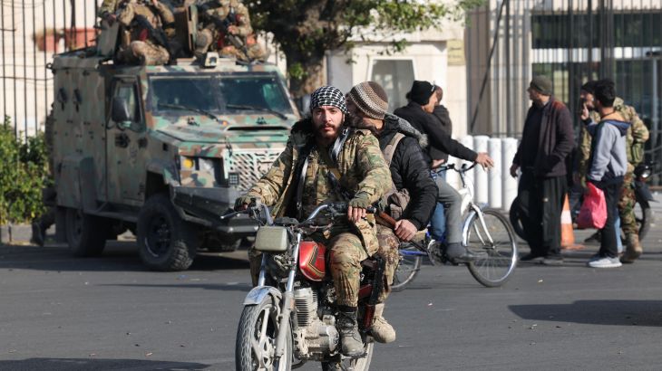 Rebel fighters ride a motorbike, after rebels seized the capital and ousted President Bashar al-Assad