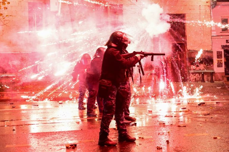 Fireworks shot by protesters explode near police in riot gear firing tear gas during a fourth day of nationwide protests