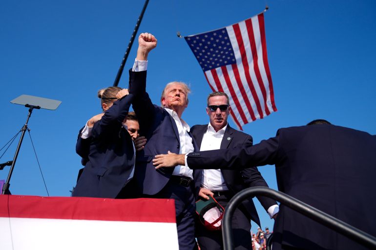 Republican presidential candidate former President Donald Trump gestures as he is surrounded by U.S. Secret Service agents as he leaves the stage at a campaign rally, Saturday, July 13, 2024, in Butler, Pa. (Evan Vucci/AP)