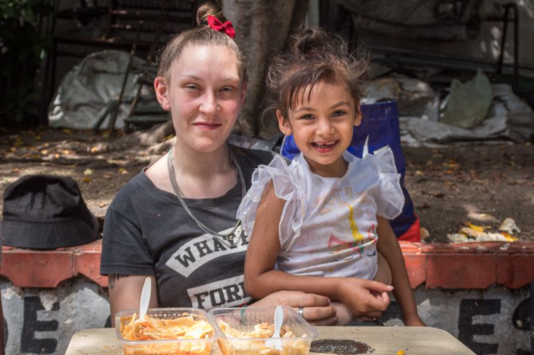 Marianela Abasto and her daughter sit in front of two trays of ravioli at an outdoor table.